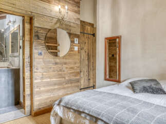 Experience rustic charm in this cozy bedroom featuring a comfortable bed adorned with a plush grey throw and accent pillow.