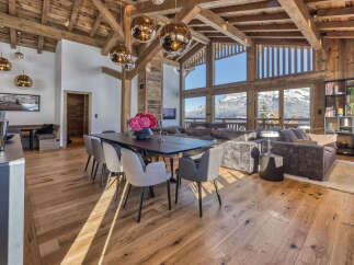 Experience luxury mountain living in this stunning chalet featuring a spacious open-plan living area with a grand dining table and plush seating.