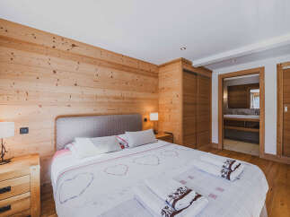 Experience rustic charm in this beautifully appointed bedroom featuring warm, natural wood paneling on the walls and a spacious, comfortable bed.