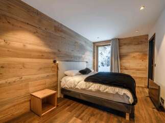 Experience cozy mountain living in this charming bedroom featuring rustic wood-paneled walls and a comfortable bed.