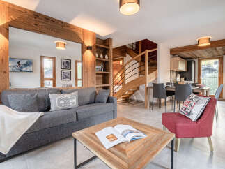 Experience alpine living in this charming mountain retreat, featuring a cozy living area with a plush sofa and a rustic wooden coffee table.
