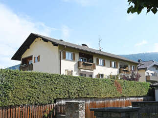 This charming property features a well-maintained exterior with a lush green hedge providing privacy and a wooden fence.