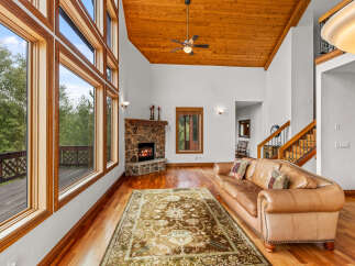 Experience luxurious living in this stunning great room, featuring a floor-to-ceiling stone fireplace and expansive windows that flood the space with natural light.