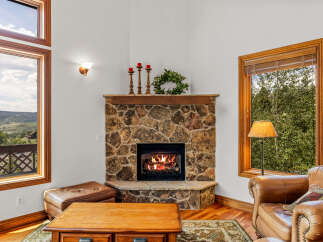 Cozy up by the stone fireplace in this inviting living room, featuring a large wooden coffee table and plush leather seating.