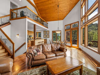 Experience luxurious mountain living in this stunning home featuring a grand living area with vaulted wood ceilings and a wall of windows showcasing breathtaking views.