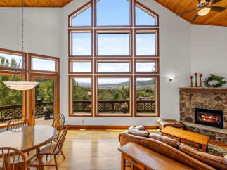 Experience breathtaking mountain views from this stunning living room, featuring a grand stone fireplace and expansive windows that flood the space with natural light.