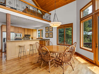 Experience breathtaking mountain views from this stunning dining area, featuring a beautiful wooden dining set and a modern chandelier.