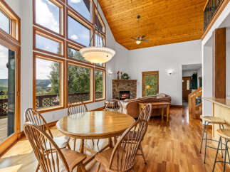 Experience breathtaking views from this stunning living space, featuring a grand stone fireplace and expansive windows that flood the room with natural light.