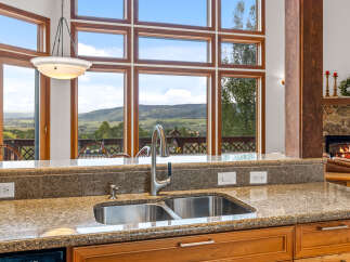 Experience breathtaking mountain views from this stunning kitchen, featuring a double stainless steel sink and granite countertops.
