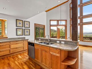 Experience breathtaking mountain views from this stunning kitchen, featuring elegant granite countertops and custom wood cabinetry.