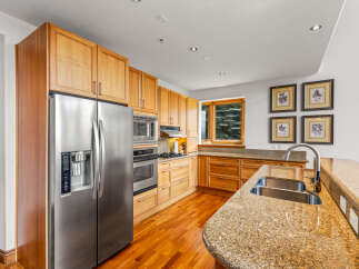 Experience the warmth of this inviting kitchen, featuring custom light wood cabinetry and gleaming granite countertops.