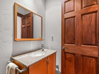 This powder room features a warm and inviting atmosphere with its rich, dark wood door and matching vanity.