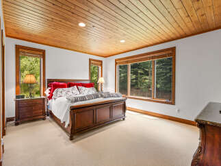 Experience serene mountain living in this charming bedroom, featuring a luxurious wooden bed frame and plush carpeting.