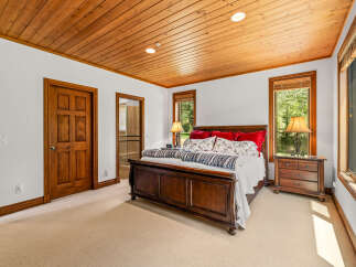 Experience ultimate comfort in this inviting bedroom, featuring a luxurious wooden sleigh bed adorned with plush red and patterned pillows.