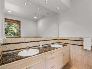 This elegant bathroom features a spacious double vanity with a granite countertop and two undermount sinks, perfect for busy mornings.