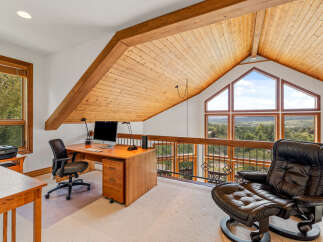 This stunning loft office space boasts a vaulted wood-paneled ceiling and expansive windows offering breathtaking mountain views.