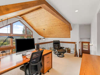 This loft office space boasts a stunning vaulted wood-paneled ceiling and expansive windows offering breathtaking mountain views.