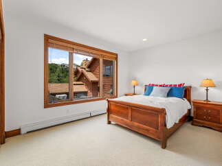 Experience comfort and style in this charming bedroom, featuring a beautiful wooden sleigh bed and a large window offering scenic views.