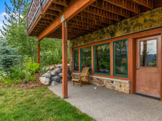 Enjoy the serene mountain views from this charming property, featuring a rustic stone exterior and a spacious wooden deck.