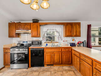 This charming kitchen features warm wooden cabinetry and a spacious countertop, perfect for meal preparation.