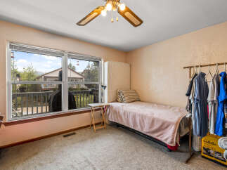 This cozy bedroom features a comfortable twin bed with a pink quilted blanket, perfect for a guest room or a child's space.