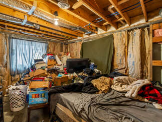 This unfinished basement space offers a unique opportunity for customization, featuring exposed wooden beams and insulation ready for your personal touch.
