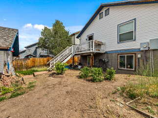 Discover the potential of this backyard, featuring a spacious deck accessible by stairs, perfect for outdoor entertaining.