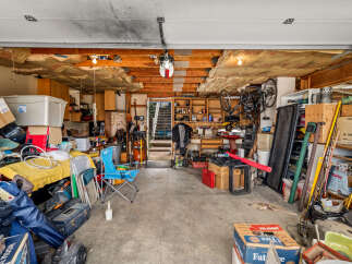 This spacious garage offers ample storage solutions with numerous shelves, cabinets, and large bins, perfect for organizing tools and equipment.