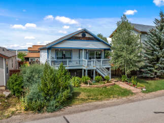 Charming home with a welcoming front porch and a spacious deck, perfect for outdoor living.