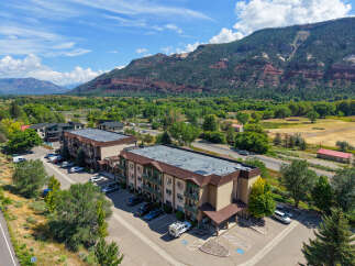 Discover this multi-story apartment complex nestled against a backdrop of majestic mountains and lush greenery.