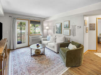 Step into this inviting living room, featuring a comfortable neutral-toned sofa and a plush green accent chair perfect for relaxation.