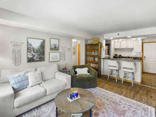 Experience comfortable living in this inviting living room, featuring a plush sofa and a cozy armchair perfect for relaxation.