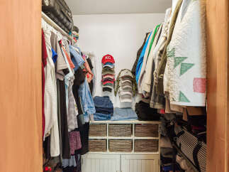 Discover ample storage solutions in this well-organized walk-in closet, featuring a spacious hanging area for clothes and a dedicated shelf for folded jeans and accessories.