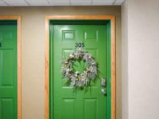 Welcome guests with a charming floral wreath on this vibrant green door, featuring a modern digital lock for enhanced security.