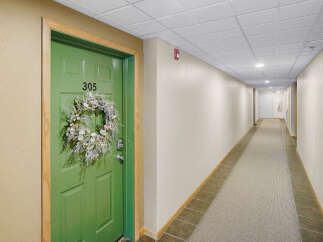 Welcome to this charming hallway featuring a vibrant green door with a decorative wreath and the number 305.