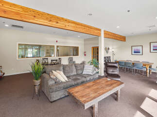 This spacious common area features a comfortable sectional sofa, a rustic wooden coffee table, and a large dining table with seating for six.