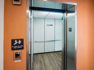 This image showcases an elevator lobby with a clear 'In Case of Fire Use Stairs' sign and a fire service operation panel, ensuring safety and accessibility.
