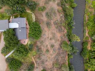 Experience serene living with this stunning aerial view of a modern home nestled beside a tranquil river.