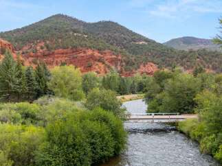 Discover this stunning property nestled beside a scenic river, offering breathtaking views of red rock formations and lush green mountains.