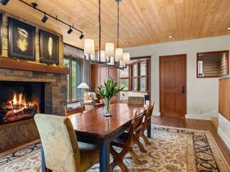 Experience rustic elegance in this dining room, featuring a grand stone fireplace and a warm, wood-paneled ceiling.