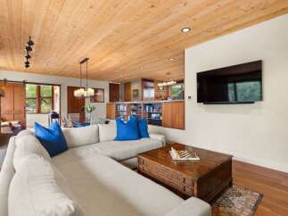 Experience rustic charm and modern comfort in this inviting living space, featuring a warm wood-paneled ceiling and a cozy sectional sofa perfect for relaxation.