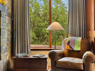 Cozy up in this inviting living space featuring a comfortable leather armchair draped with a colorful quilt.