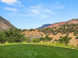 Experience breathtaking mountain views from this stunning property, featuring a lush green lawn perfect for outdoor enjoyment.