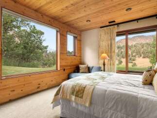 Experience breathtaking natural beauty from this stunning bedroom, featuring expansive windows that frame panoramic views of lush greenery and majestic mountains.