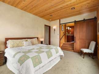 Experience rustic charm in this inviting bedroom featuring a comfortable king-sized bed adorned with a charming patchwork quilt.