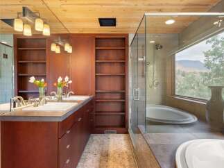Experience luxury in this stunning bathroom featuring a spacious glass-enclosed shower and a deep soaking tub with a breathtaking mountain view.