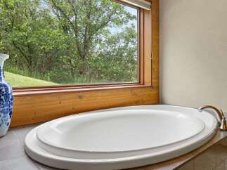 Indulge in relaxation with this stunning soaking tub, perfectly positioned to offer serene views of the lush greenery outside.