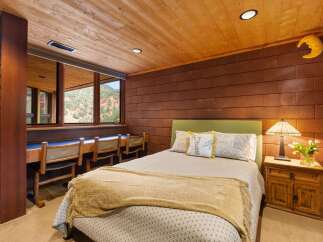 Experience rustic charm in this unique bedroom featuring a warm wood-paneled ceiling and textured brick walls.