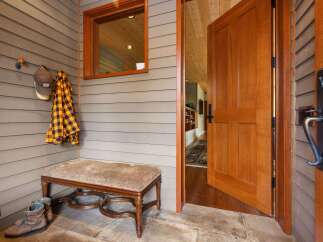 Step into this inviting entryway featuring a charming bench with a patterned cushion, perfect for removing outdoor gear.