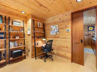 This cozy home office features warm wood paneling throughout, creating a rustic and inviting atmosphere.